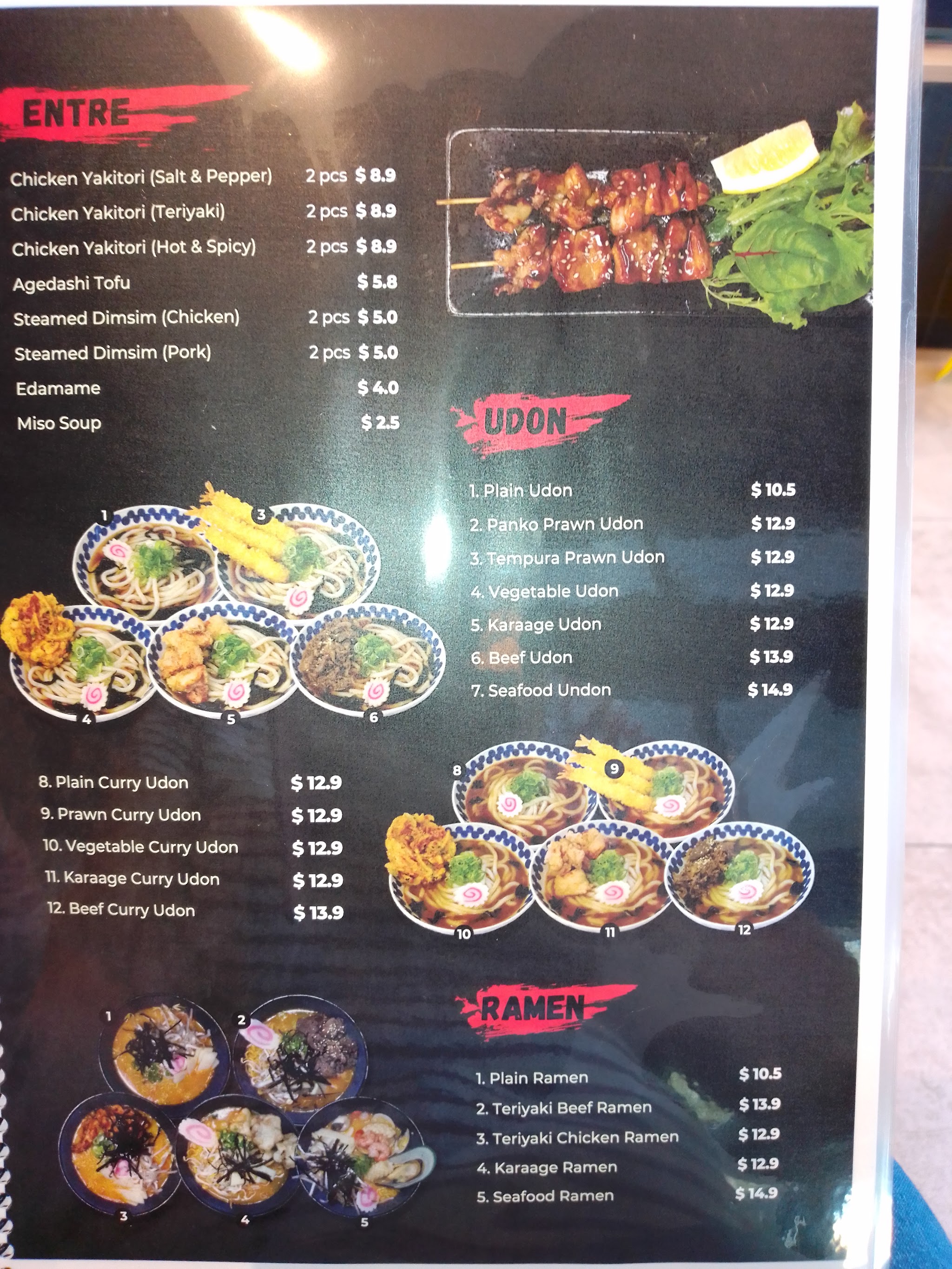 The menu board in store listing entrées, udon and ramen with prices