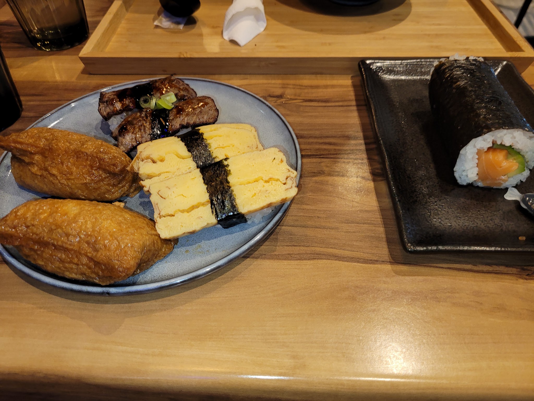 A sushi plate with inari, tamagoyaki, beef nigiri and a salmon avocado roll